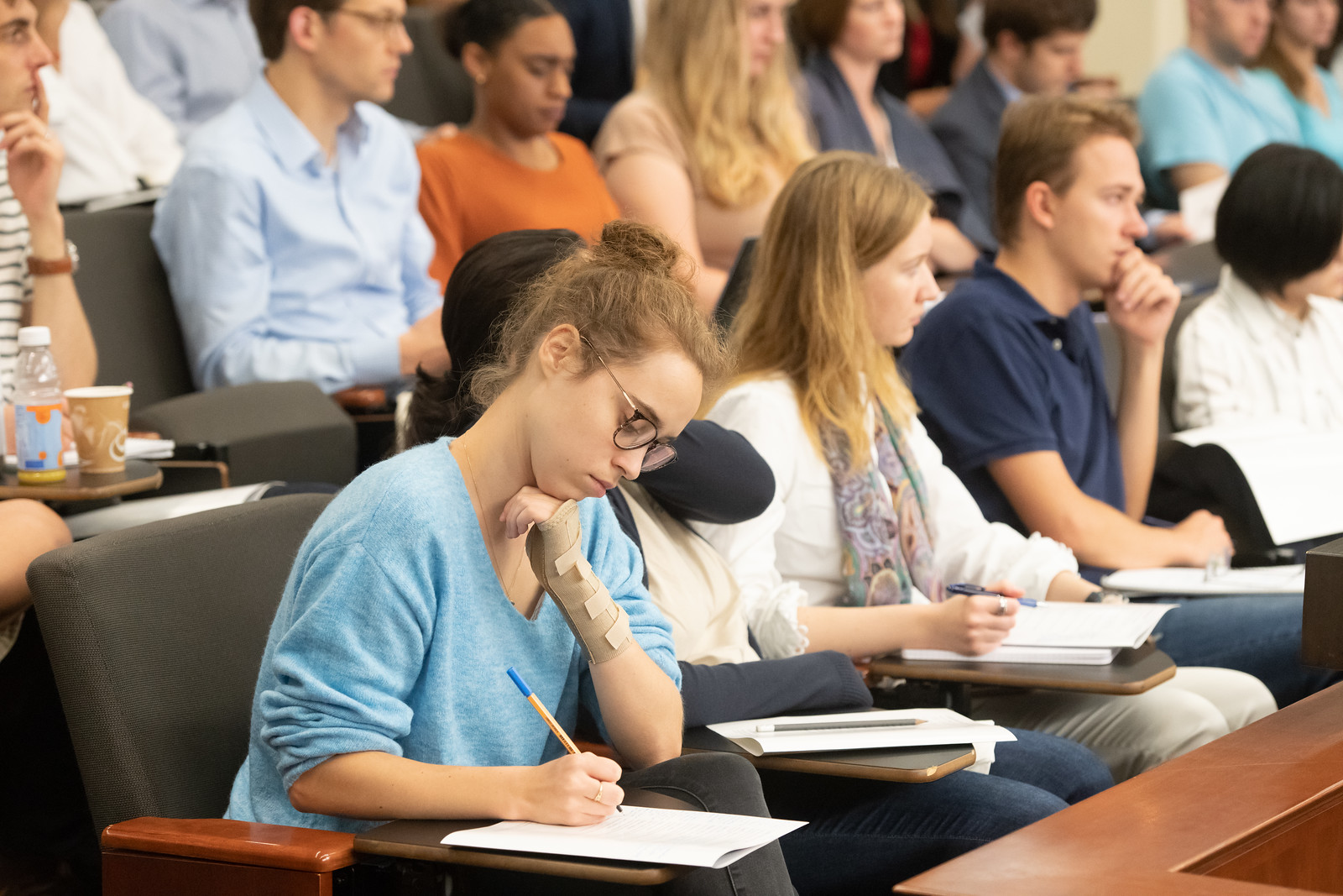 Students in lecture hall; focused on one student writing